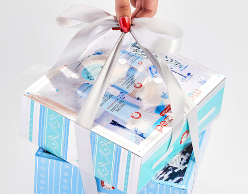 Model holding holiday gift sets bundled together with ribbon and bow.